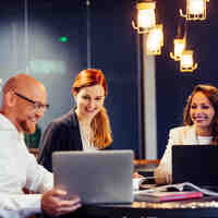 Een groep collega's in een meeting aan laptops in een vergaderruimte bij Schoevers