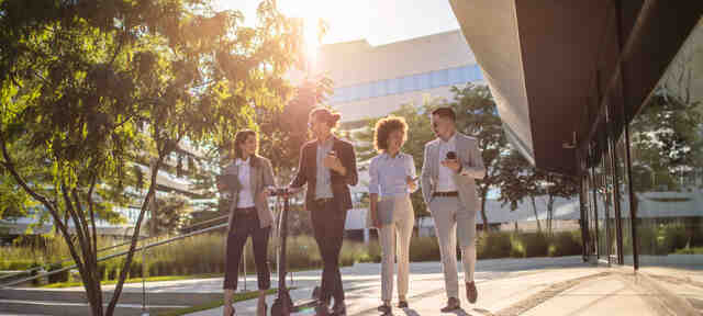 Een groep collega's lopen buiten langs het kantoor van Opleiding.nl