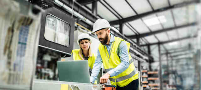 Twee procesoperators in fabriek die naar een laptop kijken