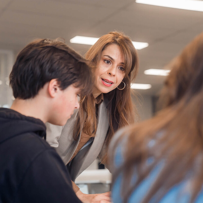 Docente geeft aan twee leerlingen uitleg bij Luzac
